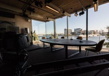 The crowdale studio, with a table and four seats. Through the large windows the river 't IJ is visible.